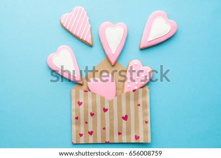 Open envelope with heart shaped cookies for Valentine day on blue surface 