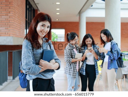 Confident beautiful female college student holding books and smiling at camera, student  Inside the school building on background, learning and education concept