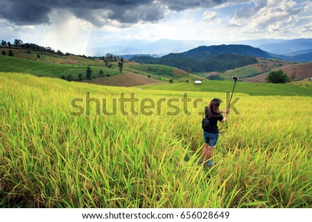 lady taking photo in rice field and mountain during storm coming