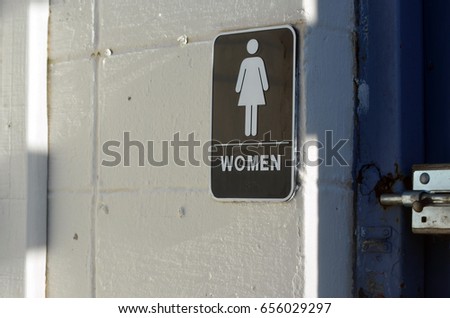 Women's restroom sign at boarded up beach pavilion 