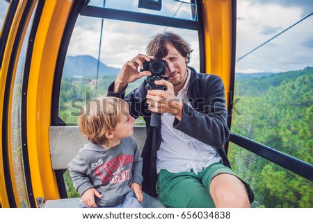Father and son in ski lift cabin in summer. Passengers on a cable car.