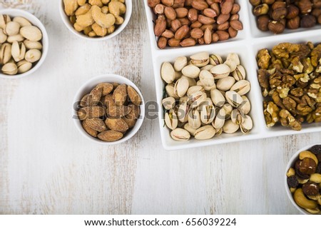 Bowls with nuts on a  wooden table. Different kinds of tasty and healthy nuts. Top view