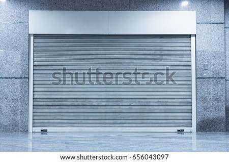Automatic Factory Shutter Roller Door Indoor, Steel Rolling Gate Door for Security System of Warehouse Storage. Architecture Metal Access Doorway With Granite Wall Background of Workshop Garage. Royalty-Free Stock Photo #656043097