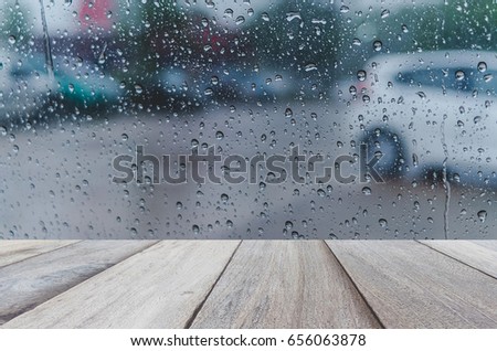 Water drops steam of rain on car windshield window glass after the rain ,Rainy background with wood terrace