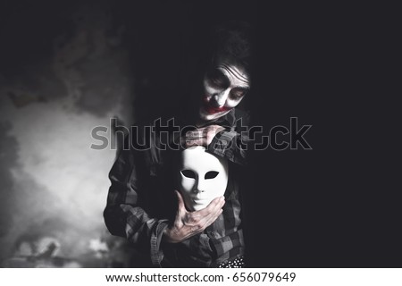 painted actor holds white mask