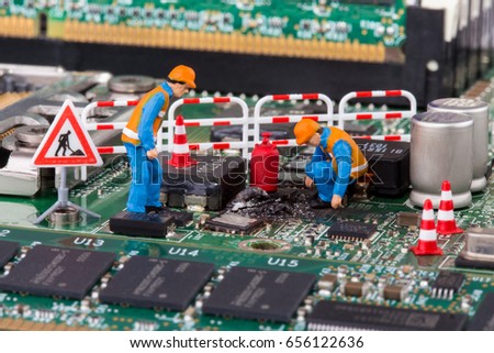 miniature workers on a computer mainboard - studio shot