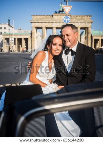 Portrait of a just married couple sitting in an oldtimer in front of the Brandenburger Gate in Berlin, Germany