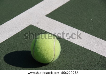 Tennis ball and white lines on green tennis court closeup