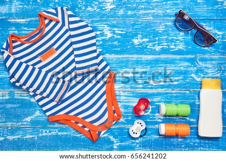 Baby Child summer stuff to the beach on a blue wooden background. Top view with copy space for text.