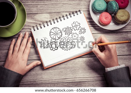 To view of businesswoman hands drawing in notepad gears mechanism