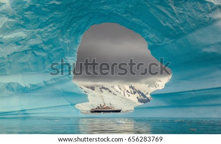 Steamer ship seen through the hole in the iceberg at Antarctic peninsula Royalty-Free Stock Photo #656283769