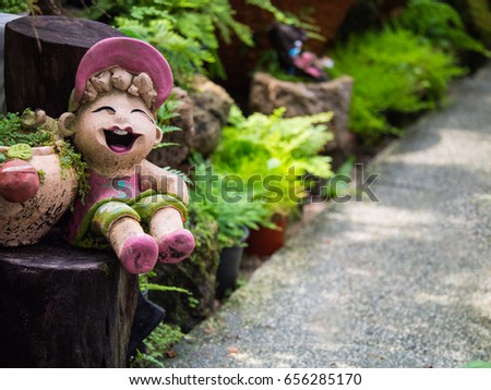 Baby Doll Wearing a Hat Sitting on a Wooden in The Garden