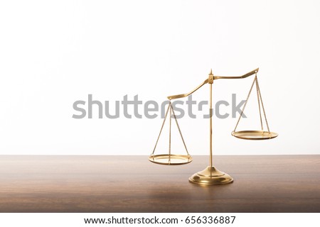 Balance scales on table with white wall background. Symbol of justice