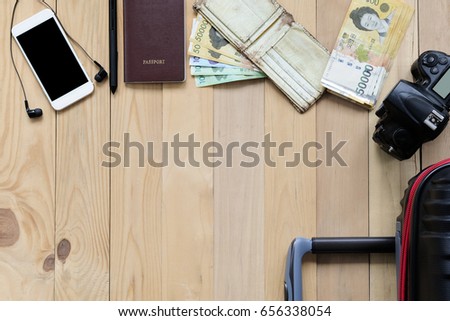 Smartphone, headphones, pencil, passport, camera, wallet with south korea banknote and luggage on wood floor. Travel background with copy space for text. Top view