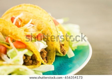 Fresh beef tacos in hard yellow corn taco shell with sour cream and shredded cheese.