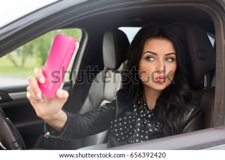 Beautiful brunette woman doing selfie in the car