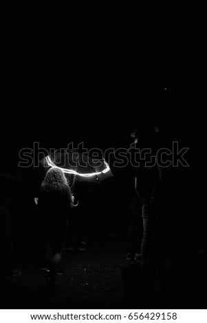 Black and white photography of a young female standing in dark with and illuminated umbrella. Dark scene. 