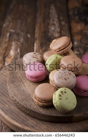 Colorful assorted macaroons on brown wooden board on brown wooden background with space for text. Rustic style