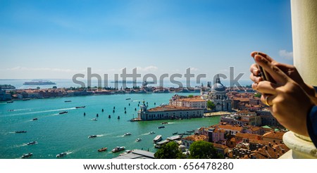 Aerial panorama of Venice at sunset,Italy and blurry hands taking picture with mobile phone from observation tower