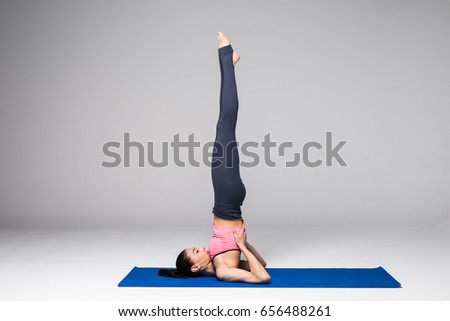 Young attractive woman practicing yoga, standing in different yoga exercise, wearing sportswear isolated on grey background.