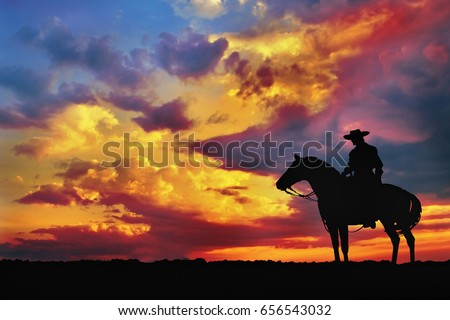 silhouette of cowboy on horse against cloudy evening sky