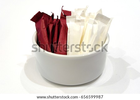 Paper packs of non-dairy creamer and sugar in bowl isolated Royalty-Free Stock Photo #656599987
