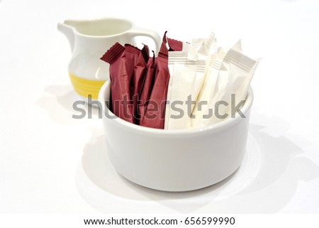 Paper packs of non-dairy creamer, sugar in bowl and milk in jar isolated Royalty-Free Stock Photo #656599990