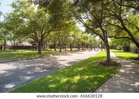Side view of asphalt road, street in suburban residential area with lot of green trees in Katy, Texas, US. America is an excellent green and clean country. Environmental and transportation background. Royalty-Free Stock Photo #656630128