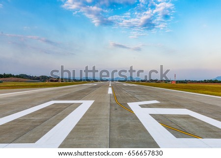 Runway, airstrip in the airport terminal with marking on blue sky with clouds background. Travel aviation concept. Royalty-Free Stock Photo #656657830