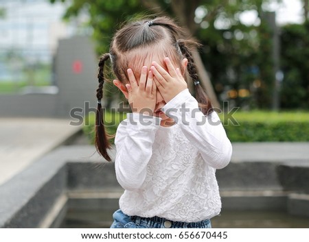 Asian little girl cover her face with her hands