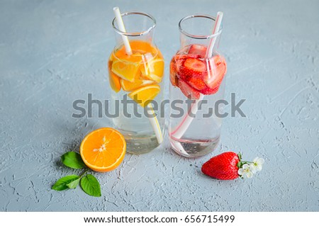 Detox water with fruits and berries in bottles on a table in front of window 