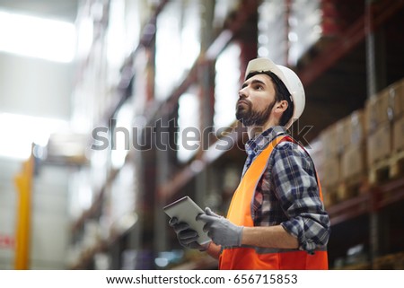 Worker with touchpad revising goods in storehouse Royalty-Free Stock Photo #656715853