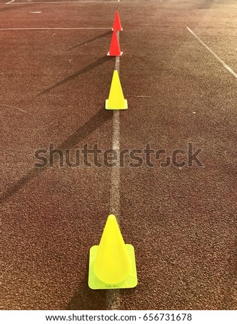 Yellow and red  fitness market cones set on red floor at sport stadium.