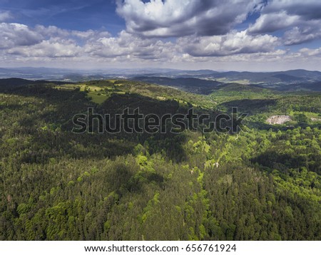 Aerial view of the summer time in mountains near Czarna Gora mountain in Poland. Pine tree forest and clouds over blue sky. View from above.