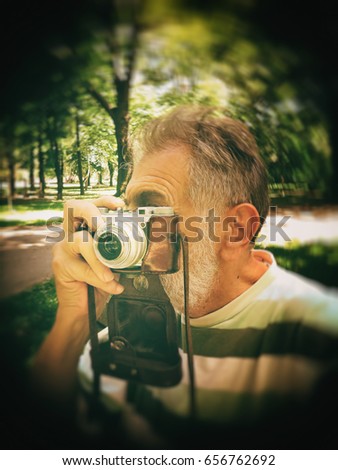 A man photographs with an old camera in the park, background, texture, blurred image