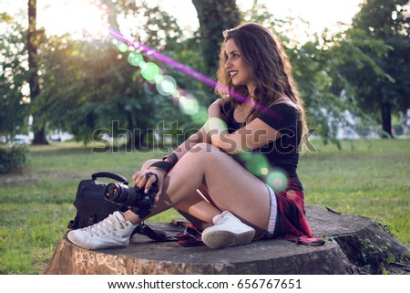 Female photographer with a professional camera and bag. Lens flare in the background.