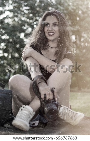 Portrait of a beautiful female photographer with a professional camera. Woman photographer with a professional camera and bag. Vintage style photo.
