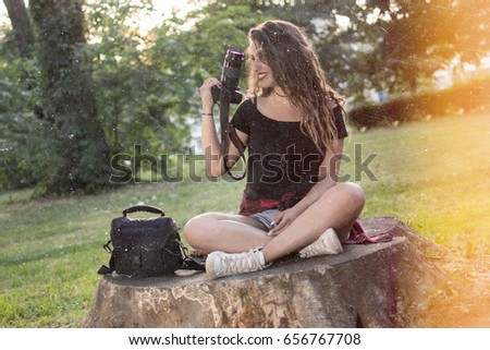 Portrait of a beautiful female photographer with a professional camera. Woman photographer with a professional camera and bag. Vintage style photo.
