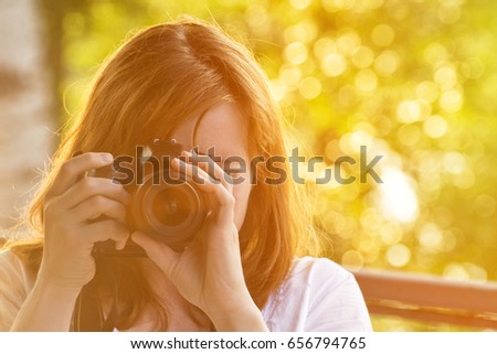 Girl photographer takes pictures against the background of greenery. Front view