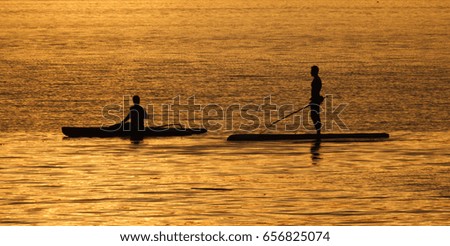 two Men playing the Paddle Board with sunset backgrounds