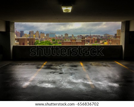 Colorful Photo of a View of the City of Baltimore from a Parking Garage - with a Wet, Rain Slick Floor and a Cloudy Blue Sky Over the Skyline in the Background