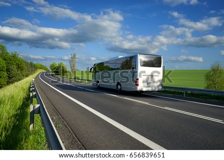 Bus traveling on the asphalt road along the green fields and alleys in the countryside Royalty-Free Stock Photo #656839651