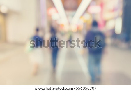 Defocused shopping mall interior with groups of people walking in pastel colors