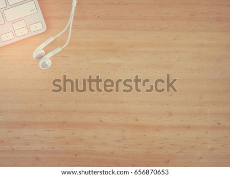 work space top view with white keyboard and ear phone on wooden background
