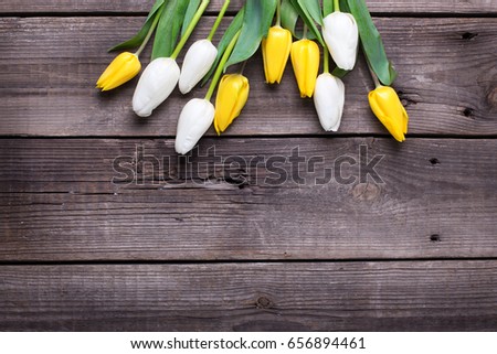 Bright yellow and white tulips flowers  on  vintage wooden background. Selective focus. Place for text. Flat lay.
