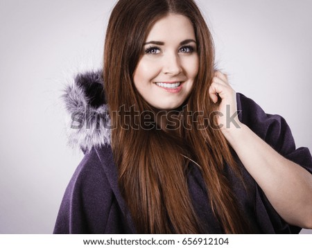 Happy woman wearing dark poncho with furry hood. Winter fashion, trendy clothing outfits concept.