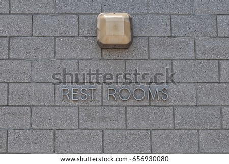 Restrooms sign on the concrete brick wall with lamp