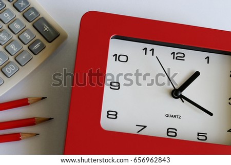 Big red clock, calculator,and red pencils on plain background. Time is money concept.