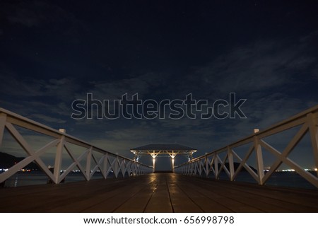 white wooden bridge at night with blue sky. way to pavilion on the sea with blue sky at night. chonburi thailand.