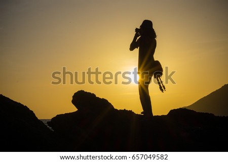 Backlight photographer standing on the mountain shooting at sun, isolated